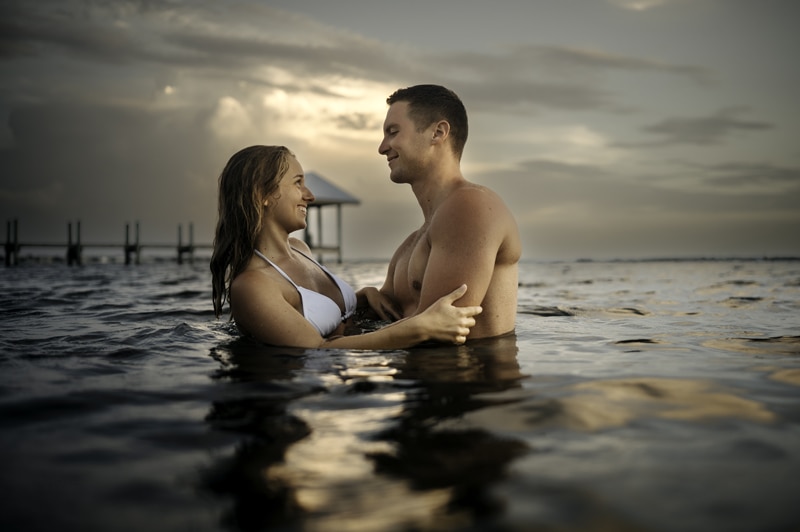 Couples Photographer, man and woman are in the ocean water and gaze at each other