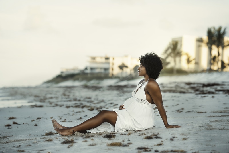 Maternity Photographer, woman reclines in the san at beach